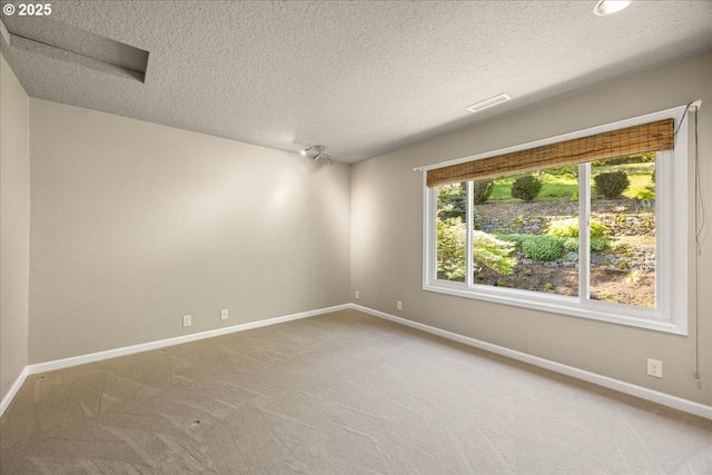 carpeted spare room with baseboards, a textured ceiling, and visible vents