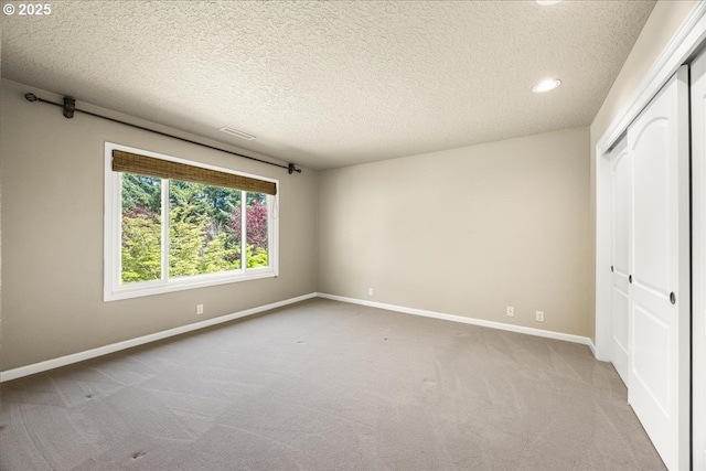 unfurnished bedroom with a textured ceiling, baseboards, a closet, carpet flooring, and recessed lighting