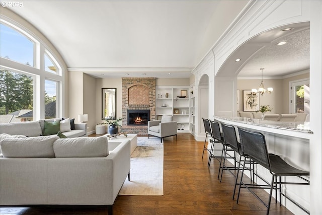living area with built in features, a fireplace, dark wood finished floors, a notable chandelier, and recessed lighting