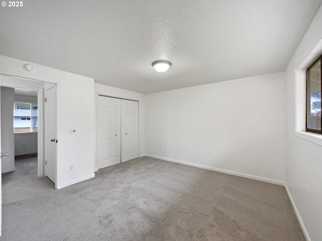 unfurnished bedroom featuring light carpet, a textured ceiling, and a closet