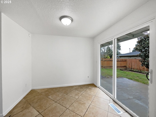 empty room with light tile patterned floors and a textured ceiling