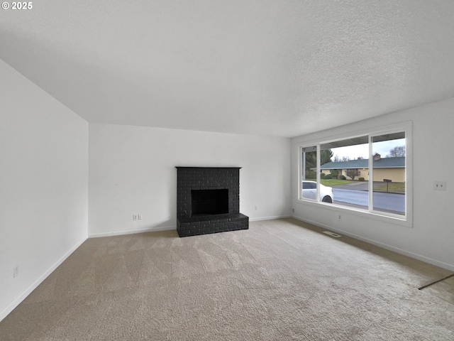 unfurnished living room featuring a brick fireplace, light carpet, and a textured ceiling