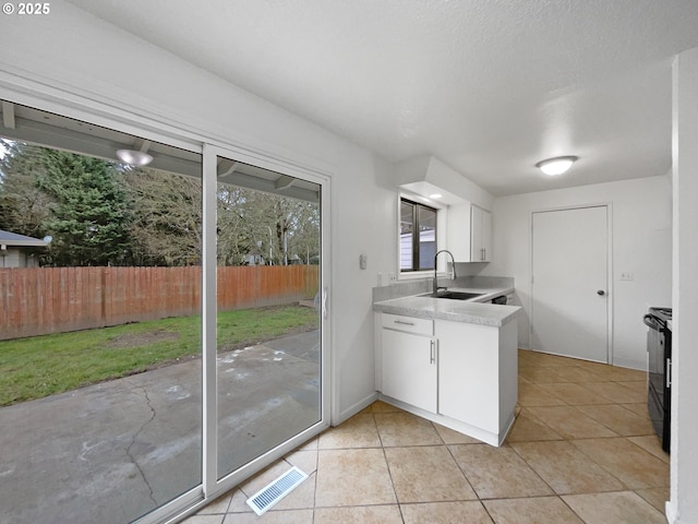 kitchen featuring white cabinetry, black / electric stove, light tile patterned floors, and sink