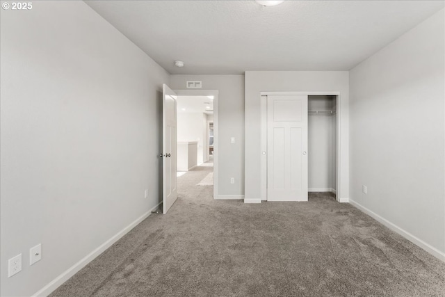 unfurnished bedroom featuring carpet floors, baseboards, visible vents, and a closet