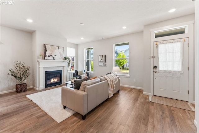 living area with light wood-style floors, recessed lighting, baseboards, and a glass covered fireplace