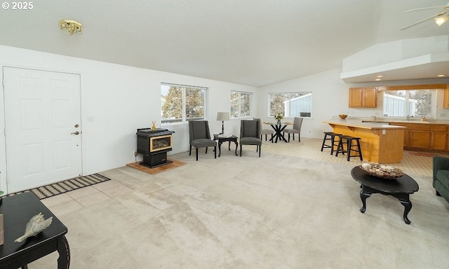 carpeted living room featuring vaulted ceiling and a wood stove