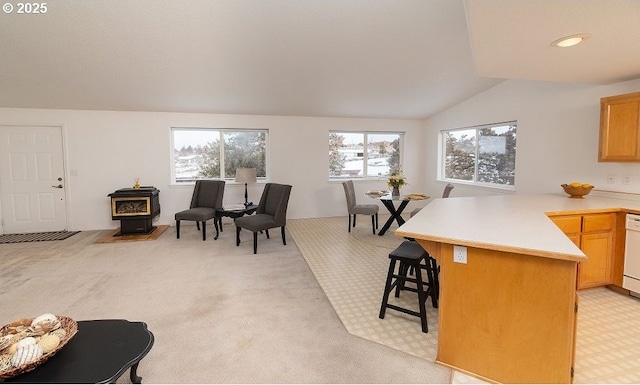 dining room featuring vaulted ceiling, light colored carpet, and a wood stove