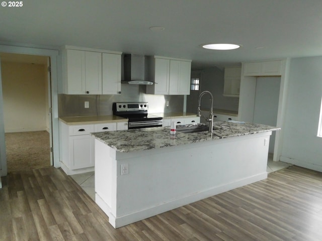 kitchen featuring white cabinetry, a center island with sink, wall chimney exhaust hood, and stainless steel electric range oven