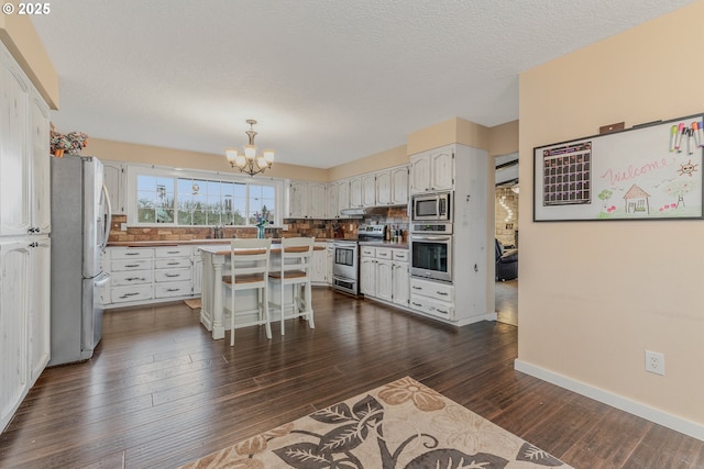 kitchen featuring a kitchen island, white cabinetry, a chandelier, a kitchen bar, and stainless steel appliances