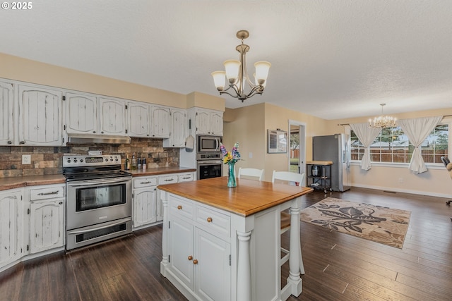 kitchen with white cabinetry, an inviting chandelier, pendant lighting, stainless steel appliances, and backsplash