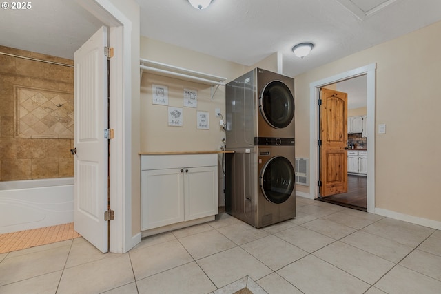 laundry room with cabinets, stacked washing maching and dryer, and light tile patterned floors