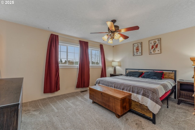 carpeted bedroom featuring ceiling fan and a textured ceiling