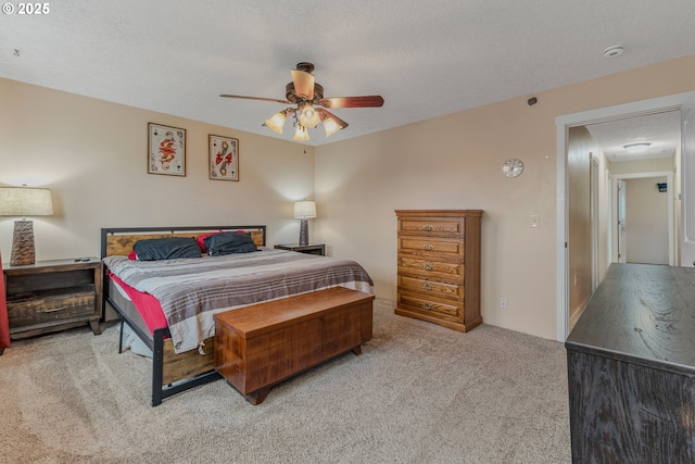 bedroom with ceiling fan, light colored carpet, and a textured ceiling