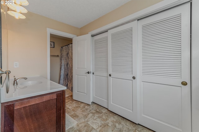 bathroom featuring vanity, a chandelier, and a textured ceiling