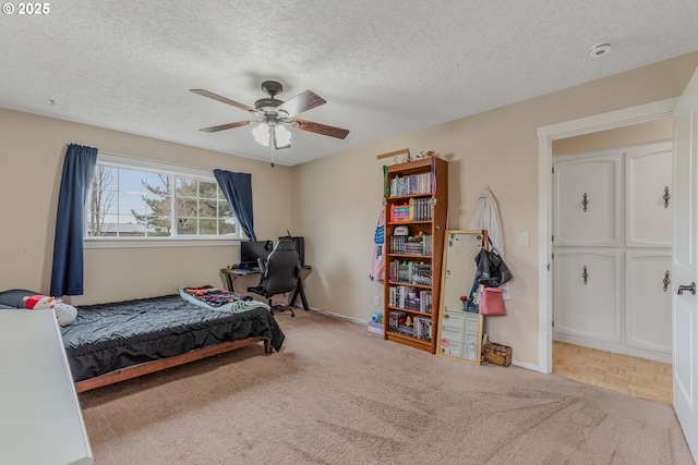 carpeted bedroom with ceiling fan and a textured ceiling