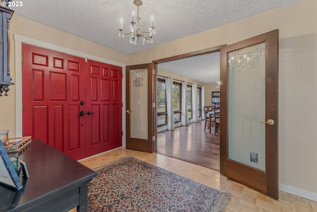 entrance foyer featuring an inviting chandelier, a textured ceiling, and light parquet floors