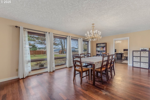 dining room with dark hardwood / wood-style flooring, a chandelier, and a textured ceiling