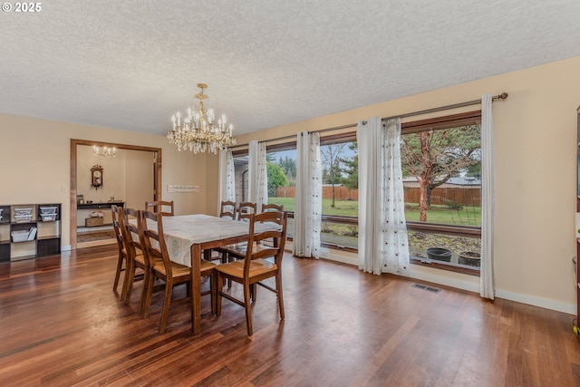 dining room featuring a chandelier, a textured ceiling, and dark hardwood / wood-style flooring