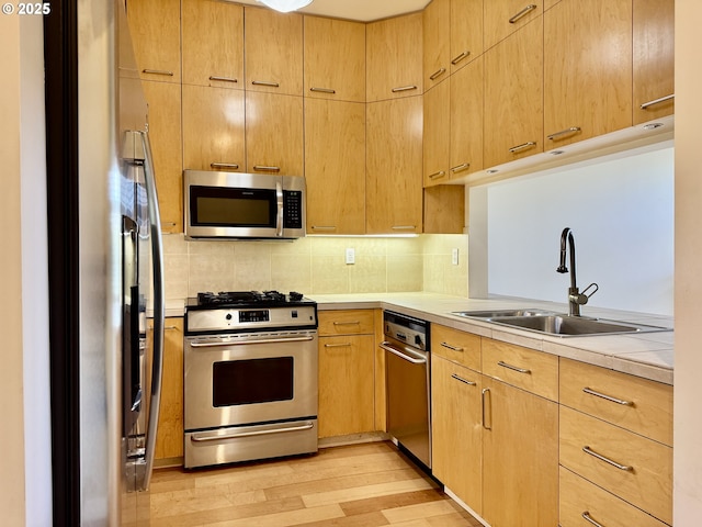 821 NW 11th Ave Unit 315, Portland, OR 97209 - kitchen with appliances with stainless steel finishes, a sink, light wood-style floors, light countertops, and tasteful backsplash