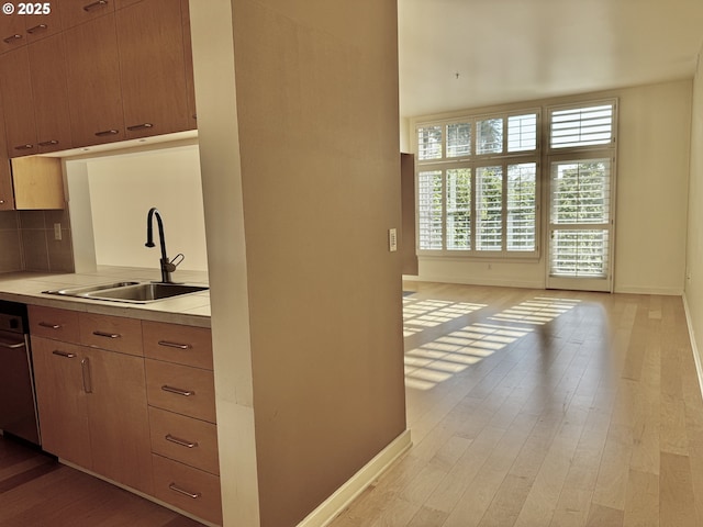 821 NW 11th Ave Unit 315, Portland, OR 97209 - kitchen with a sink, baseboards, light wood-type flooring, light countertops, and tasteful backsplash