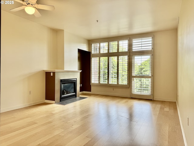 821 NW 11th Ave Unit 315, Portland, OR 97209 - unfurnished living room featuring a fireplace with flush hearth, wood finished floors, ceiling fan, and baseboards