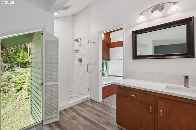 bathroom with a washtub, visible vents, wood finished floors, a shower stall, and vanity
