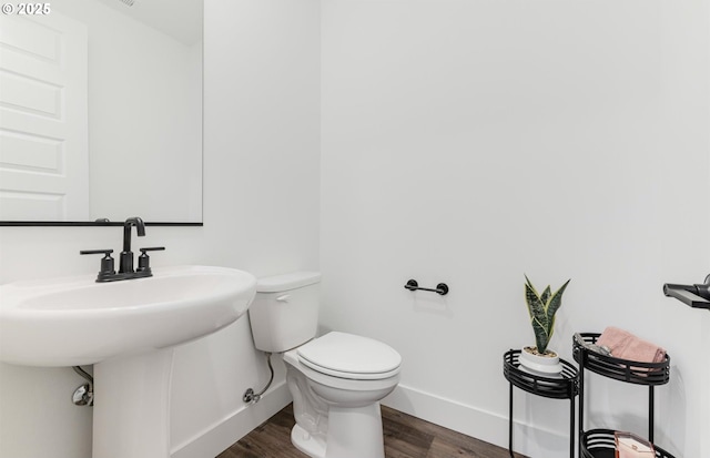 half bath featuring toilet, wood finished floors, and baseboards