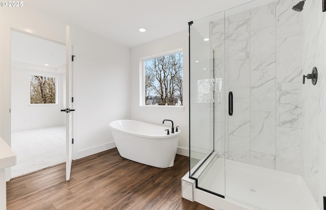 full bath with a freestanding tub, wood finished floors, recessed lighting, a shower stall, and baseboards