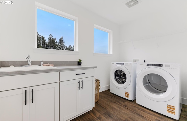 clothes washing area with visible vents, dark wood-type flooring, independent washer and dryer, a sink, and cabinet space