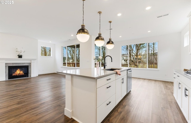 kitchen featuring a tiled fireplace, wood finished floors, visible vents, a sink, and dishwasher