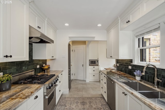 3622 NE Hassalo St, Portland, OR 97232 - kitchen with appliances with stainless steel finishes, under cabinet range hood, arched walkways, recessed lighting, and white cabinetry