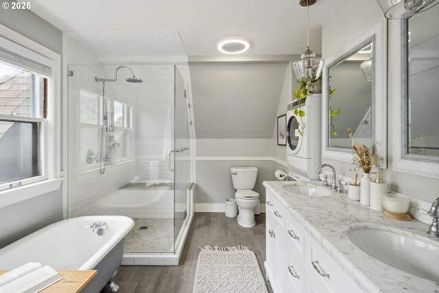 3622 NE Hassalo St, Portland, OR 97232 - bathroom featuring stacked washing machine and dryer, a shower stall, a freestanding bath, wood finished floors, and double vanity