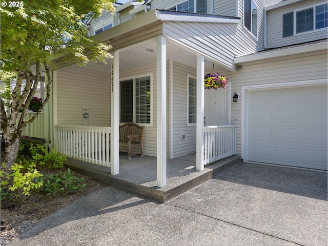 view of exterior entry featuring a garage, driveway, and covered porch