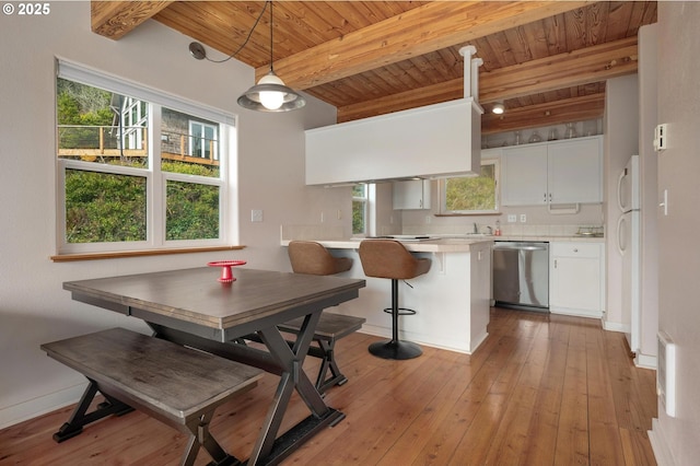 dining space featuring wooden ceiling, light wood finished floors, plenty of natural light, and beamed ceiling