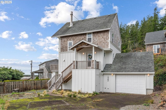 view of front facade with a shingled roof, stairway, an attached garage, fence, and board and batten siding