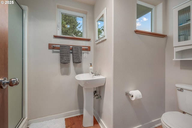 bathroom with wood finished floors, an enclosed shower, toilet, and baseboards