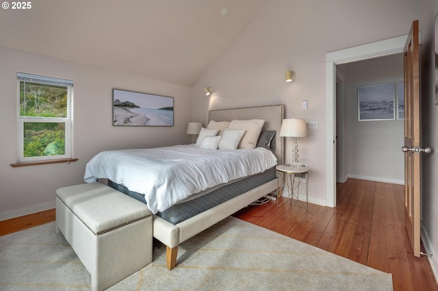 bedroom with vaulted ceiling, baseboards, and hardwood / wood-style flooring