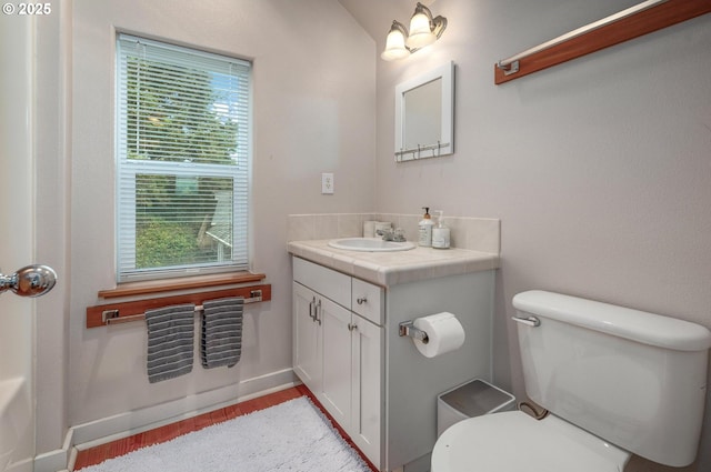 bathroom with toilet, baseboards, wood finished floors, and vanity