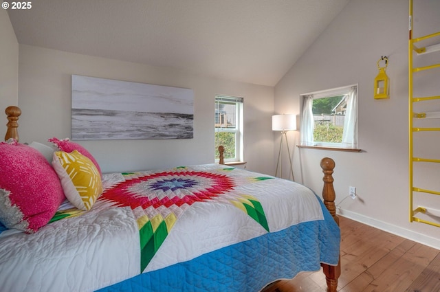 bedroom featuring lofted ceiling, baseboards, and wood finished floors