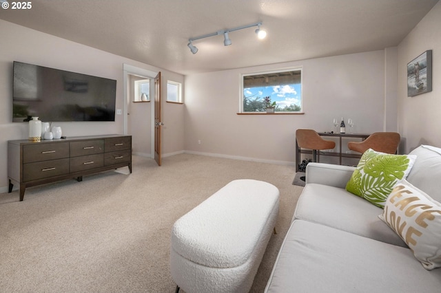 living area with rail lighting, light colored carpet, and baseboards