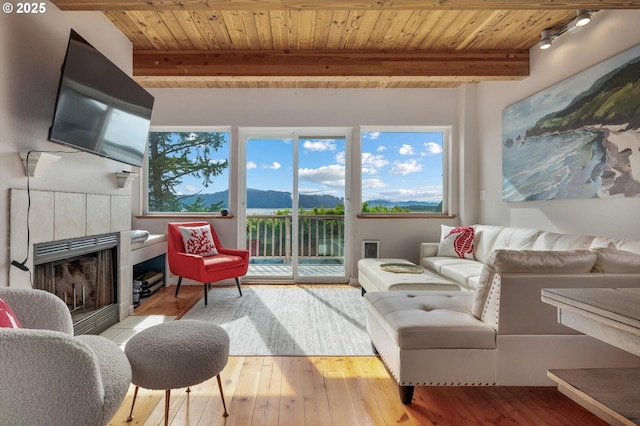 sunroom featuring a tiled fireplace, wooden ceiling, and beam ceiling