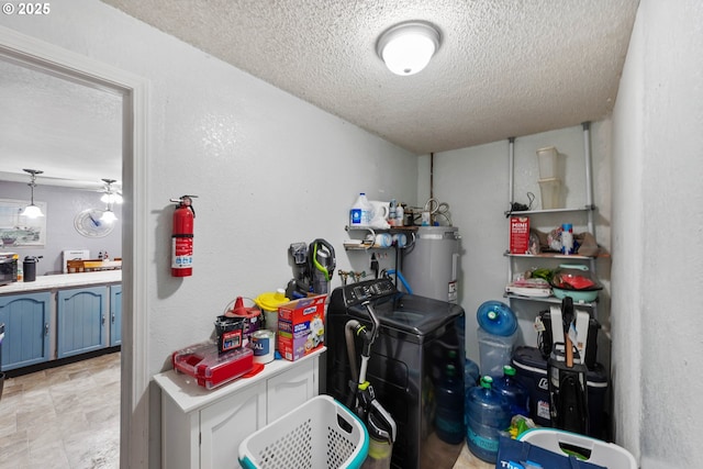 interior space with pendant lighting, washing machine and dryer, water heater, and a textured ceiling