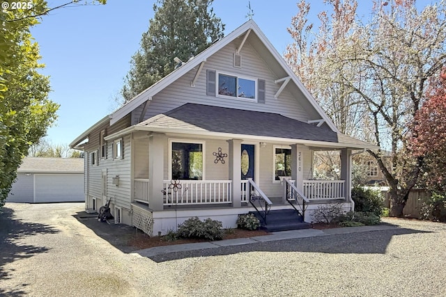 view of front of house with covered porch, a shingled roof, an outdoor structure, and a detached garage