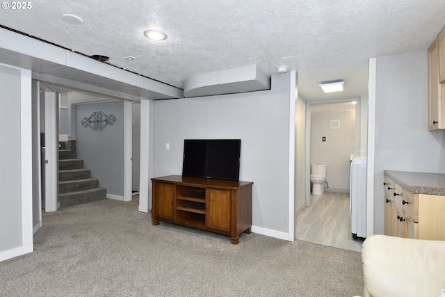 living room with light colored carpet, a textured ceiling, baseboards, stairs, and washer / dryer