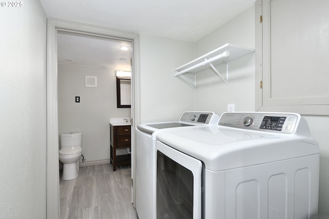 laundry room featuring separate washer and dryer, light wood-style floors, and baseboards
