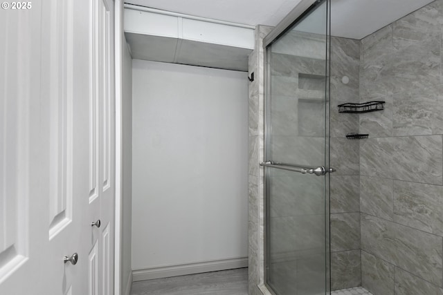 bathroom with a shower stall and baseboards