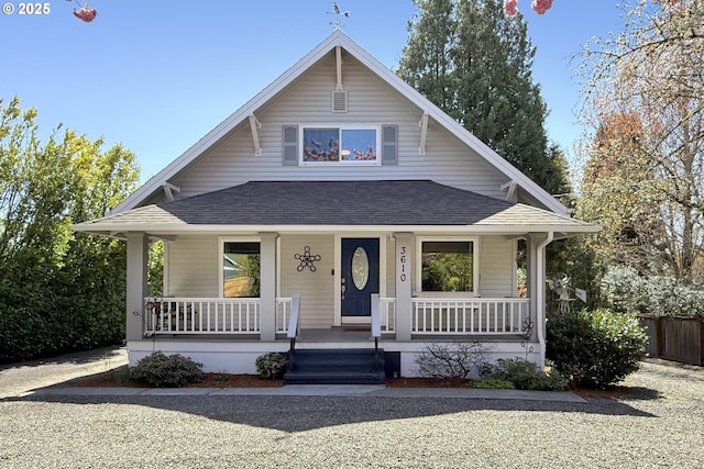 bungalow-style house with roof with shingles, covered porch, and fence