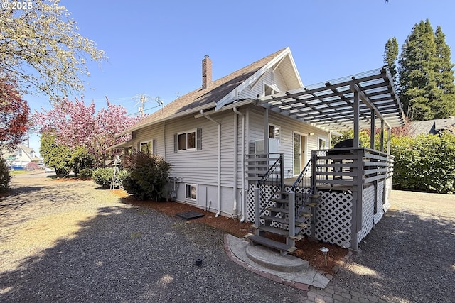 view of side of property with a chimney, a deck, and a pergola