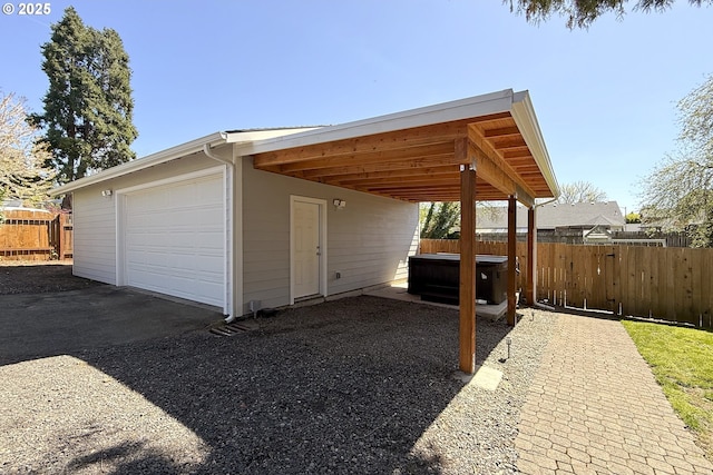 view of home's exterior with a hot tub, fence, asphalt driveway, and a garage