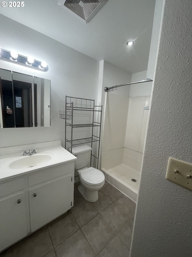 bathroom with tile patterned floors, toilet, a shower, a textured ceiling, and vanity